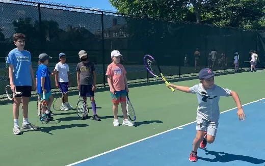 a group of kids playing tennis