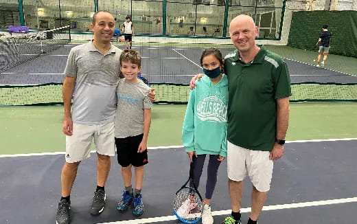 a group of people standing on a tennis court