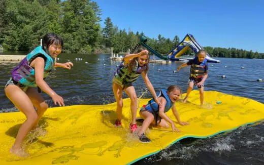 a group of kids on a yellow raft in a lake