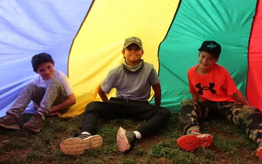 a group of boys sitting in front of a tent