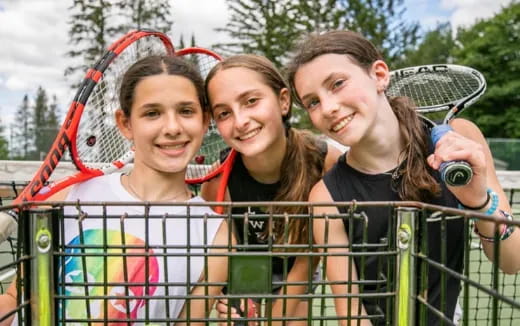 a group of girls smiling and holding tennis rackets