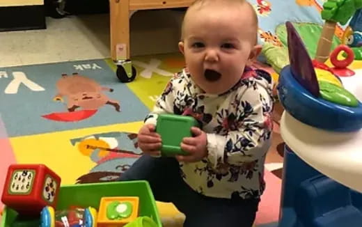 a baby holding a green toy