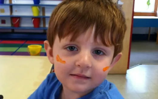 a boy with orange paint on his face