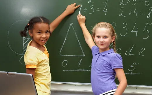 a few young girls writing on a chalkboard