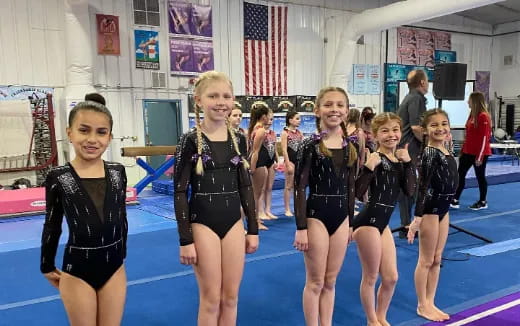 a group of girls in leotards in a gym