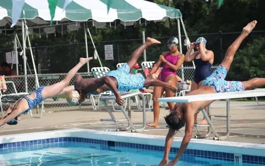 a group of people jumping into a pool
