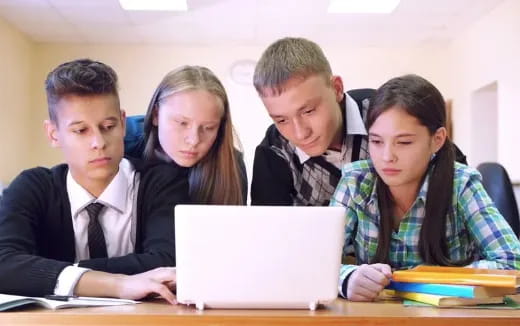 a group of people looking at a laptop