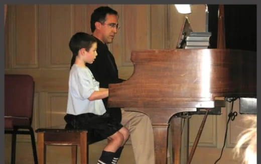 a man and a boy playing a piano