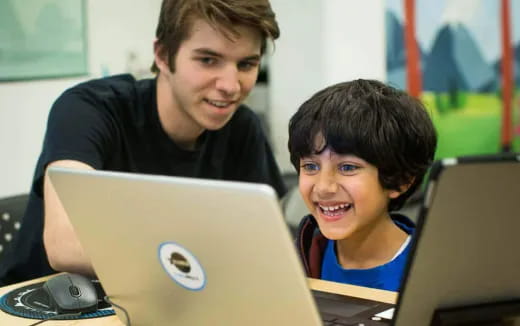 a person and a boy looking at a laptop