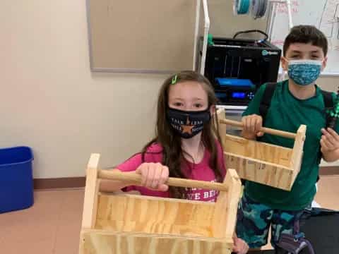 a group of kids wearing masks and holding a box