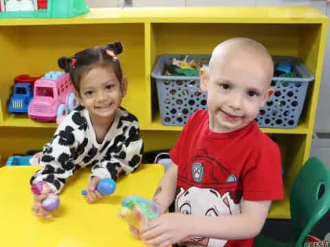 a couple of children sitting at a table with toys