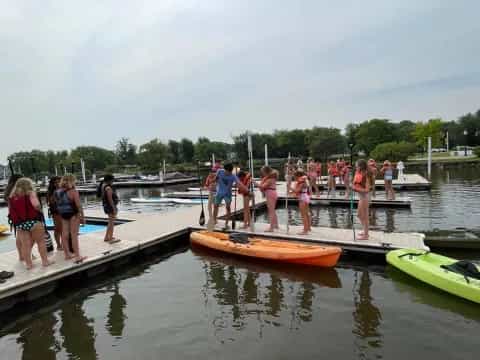 a group of people standing on a dock next to a body of water
