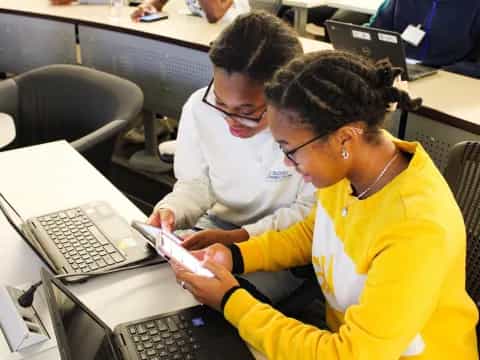 a couple of women looking at a laptop