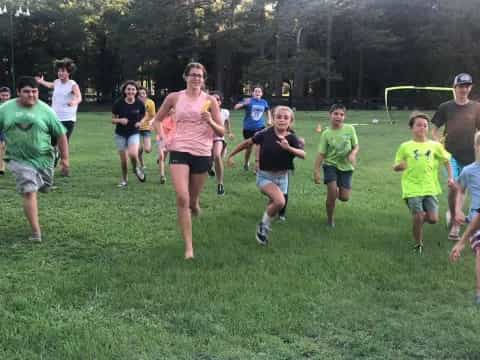 a group of people running on a grass field