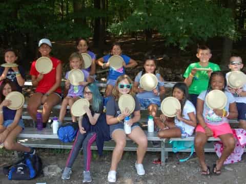 a group of people sitting on a bench holding frisbees