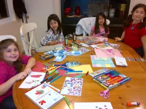 a group of girls sitting at a table with colorful paper on it