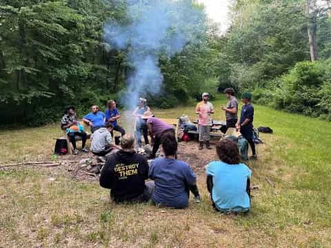 a group of people sitting on a picnic table in a forest