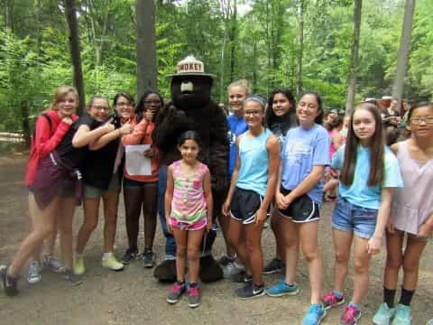 a group of people posing for a photo in front of a person in a bear garment