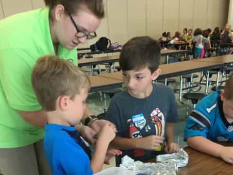 a person and two boys sitting at a table