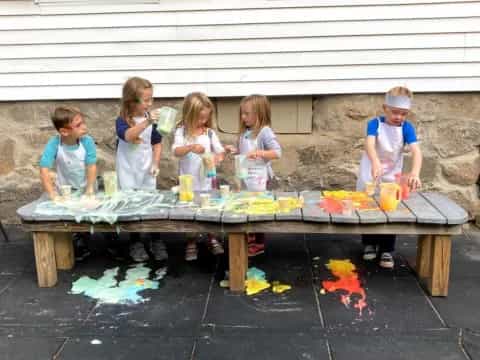 a group of children sitting at a table with food and drinks