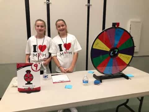 a couple of women standing next to a table with a large colorful globe