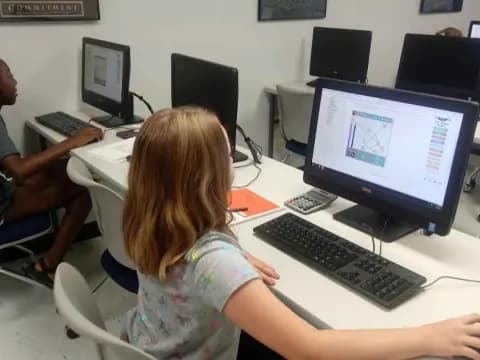 a group of people sitting at a table with computers