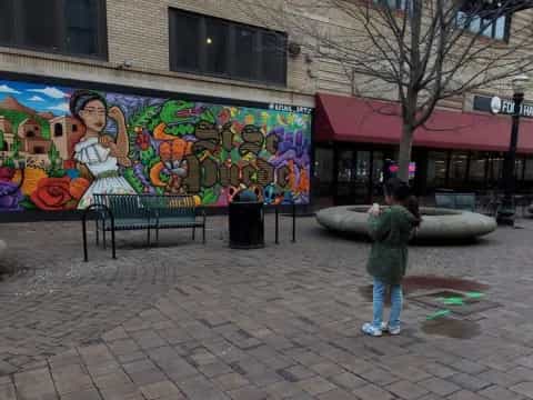 a child standing in front of a mural