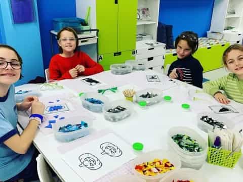 a group of children sitting at a table with food