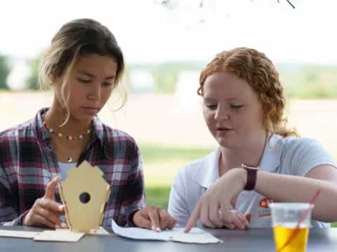 a couple of women sitting at a table looking at a paper