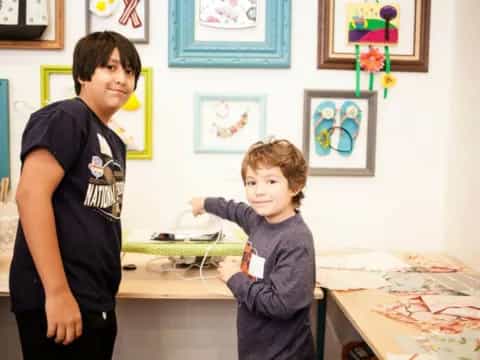a boy and a girl in a room with art on the wall