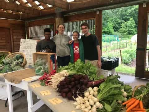 a group of people standing next to a table full of vegetables