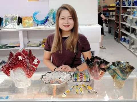 a woman sitting at a table with a large pile of toys