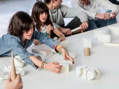 a group of people sitting around a table with white blocks