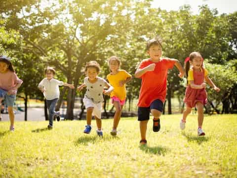 a group of children running on a grass field