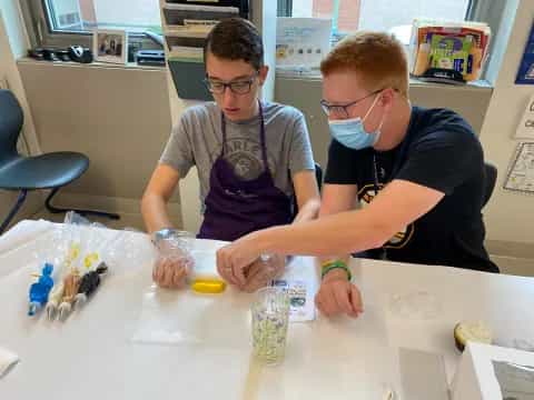 a couple of men working at a table with plastic bags of food