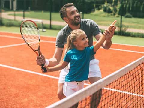 a person and a girl playing tennis