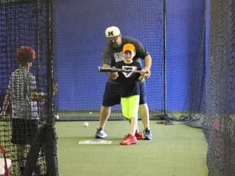 a boy hitting a ball with a baseball bat