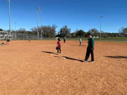 a person and a group of kids playing baseball