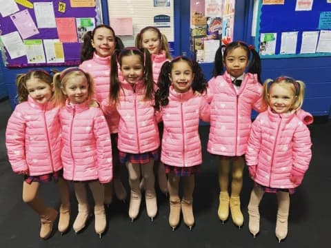 a group of girls in pink and white coats