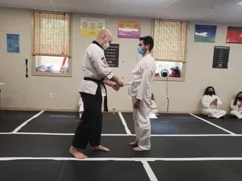 a man and a woman in karate uniforms in a room with other people