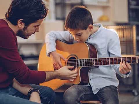a man playing a guitar with a young boy