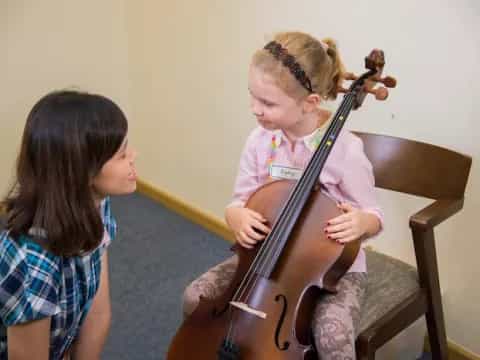 a girl playing a cello next to a girl