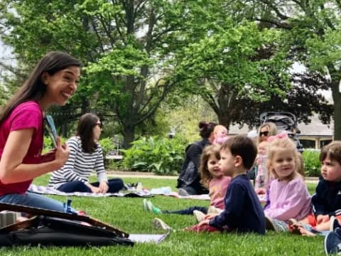 a person and a group of children sitting on the grass