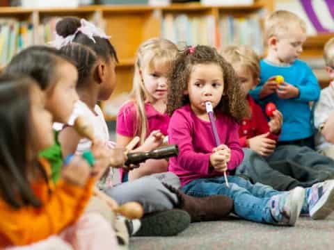 a group of children sitting on the floor with toothbrushes