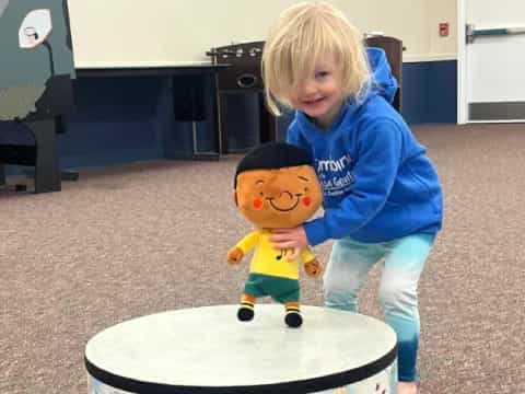 a child standing next to a stuffed toy