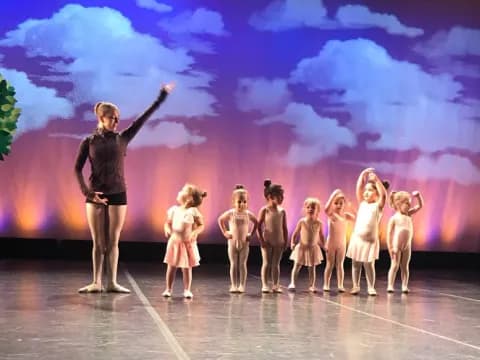 a person standing in front of a group of girls on a stage