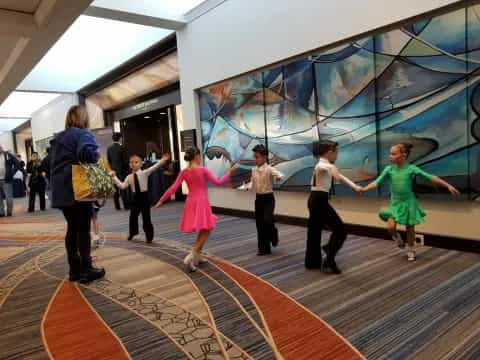 a group of people dancing in a room with a large screen