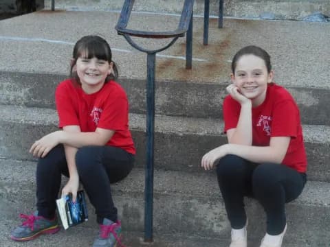 a couple of girls sitting on the ground posing for the camera