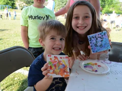 a couple of children sitting at a table with a cake