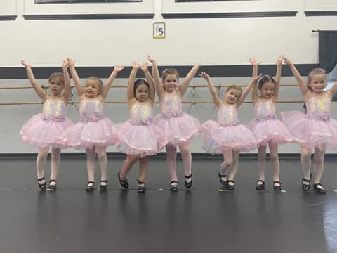 a group of girls in dresses and skirts dancing on a stage